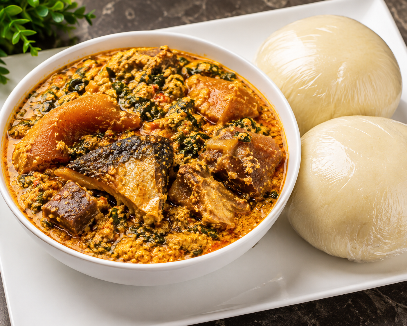 Rich egusi soup with assorted meat and fish served with two wraps of pounded yam