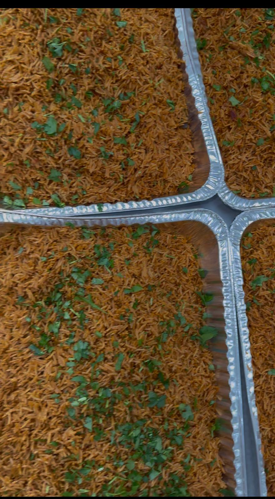 Trays of signature party jollof rice garnished with fresh herbs